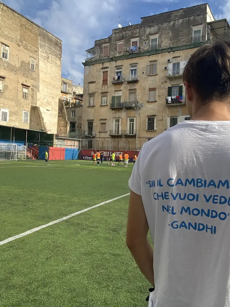 Un ragazzo di spalle a bordo campo con la maglietta Sii il cambiamento che vuoi vedere nel mondo